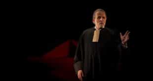 Stéphane Guillon en robe d’avocat, une main levée, dans Robert Badinter, l’enragé de justice.