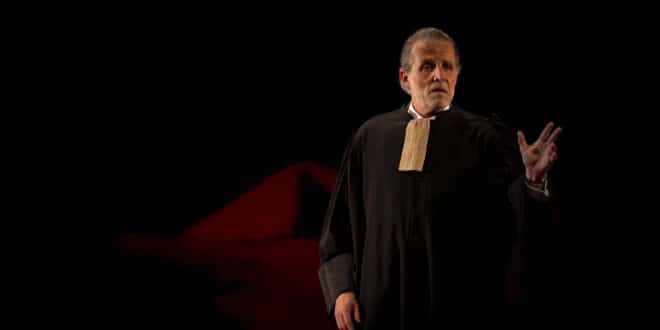 Stéphane Guillon en robe d’avocat, une main levée, dans Robert Badinter, l’enragé de justice.