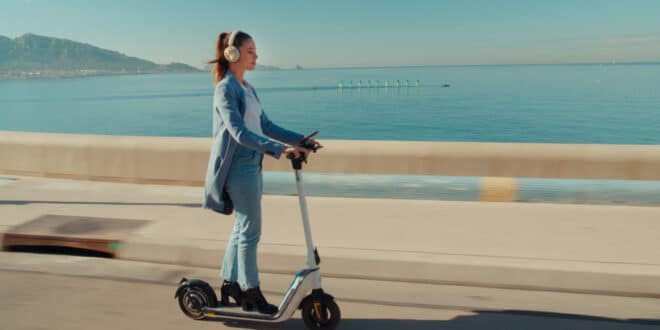 Marilou Aussilloux, casque audio sur les oreilles, à trottinette devant la mer dans Une femme aujourd’hui.